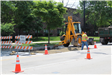 A man shoveling gravel in a hole in a road.