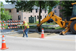 A man shoveling gravel in a road.