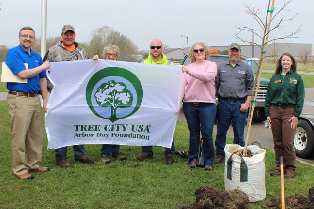 A group of people holding a Tree City USA flag.